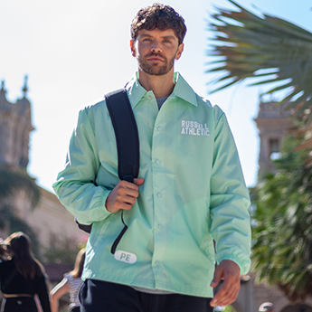 Male model wearing a mint green coaches jacket. 